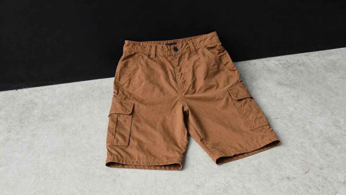 Brown cotton cargo shorts with patch pockets laid flat on concrete, showing fit and wear for a Carhartt shorts guide