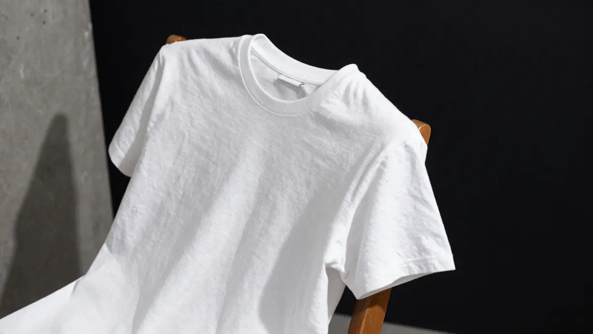 Pre-owned white cotton tee with visible fabric pilling on the sleeve laid over a wooden chair, a Stussy tee to check